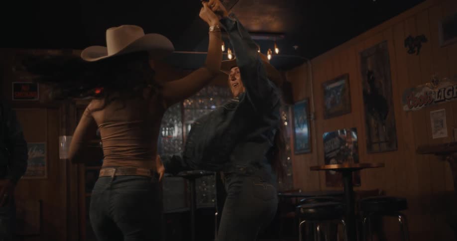 Couple dancing in a westernstyle hall with hats and low lighting