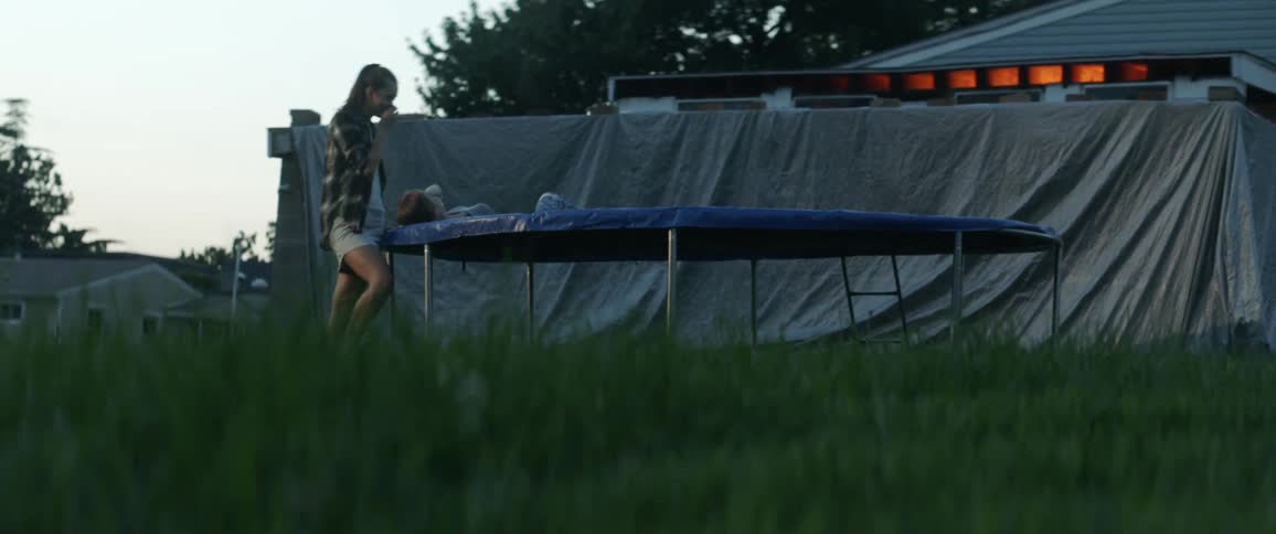 Woman laying on trampoline while another woman stands next to her