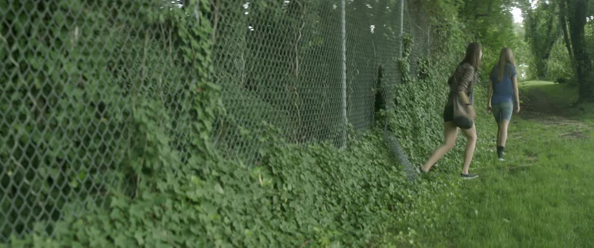 People exit out of a hole in the fence