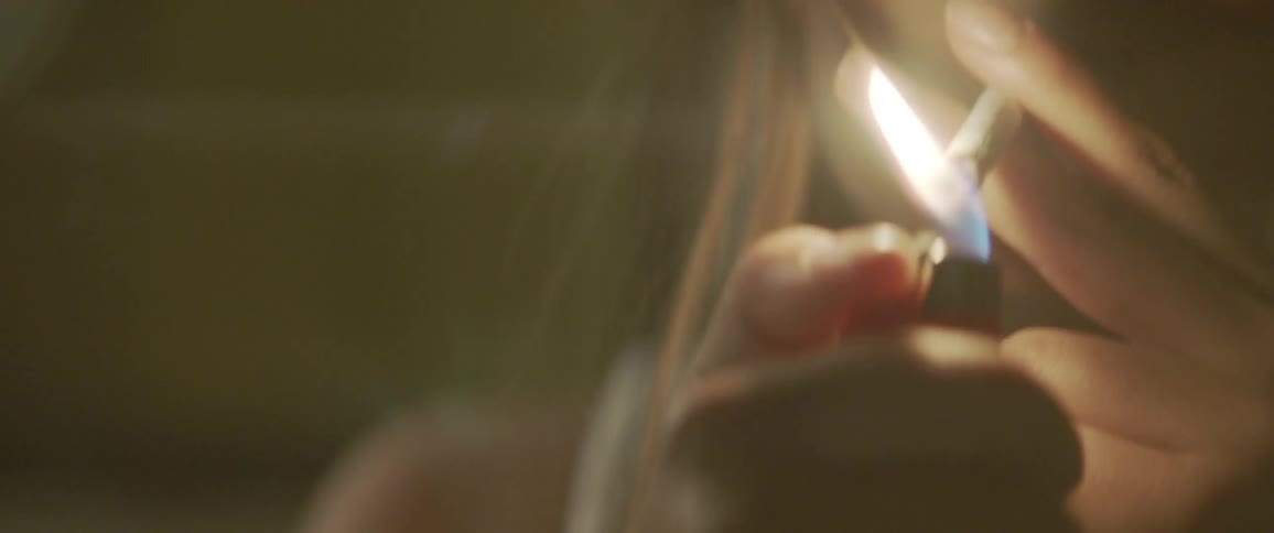 A woman lights a smoke and inhales