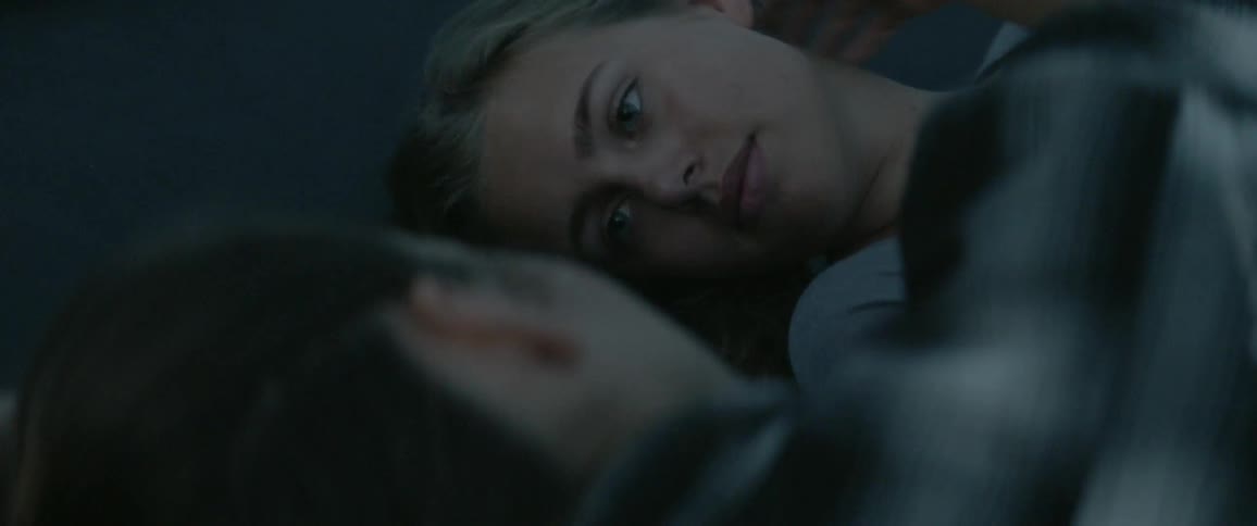 Two women lay side by side in the dark and one strokes the other's hair
