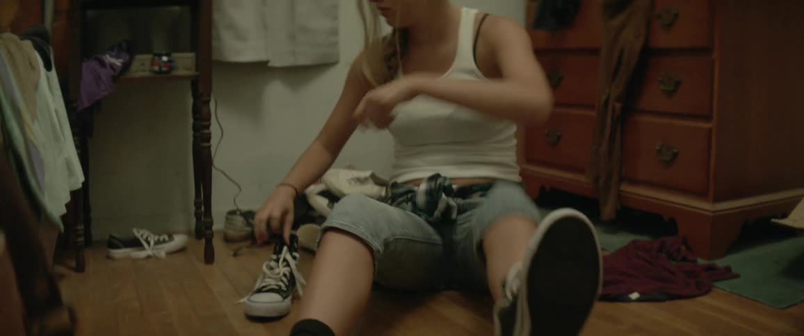 Woman puts shoes on in a bedroom
