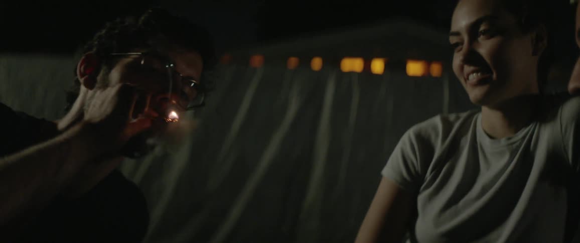 A man sitting outside gets a light for his smoke