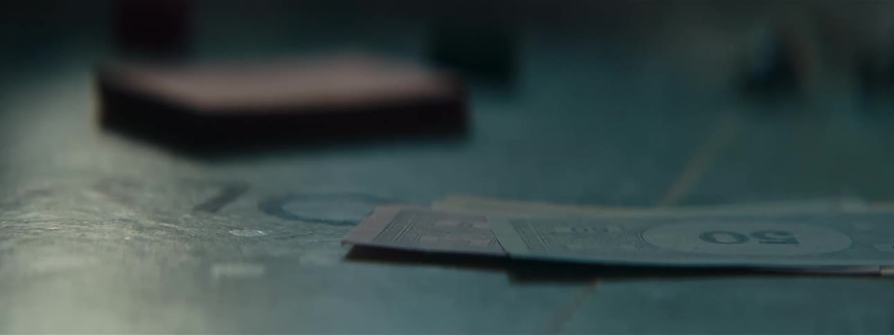 In a dimly lit room dice tumble across a board game rolling over pile of monopoly money