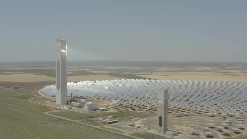 Solar power plant with concentration towers and heliostat mirrors spreads across a flat rural area