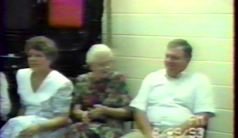A small group of people are enjoying themselves talking smiling and dancing in a small room