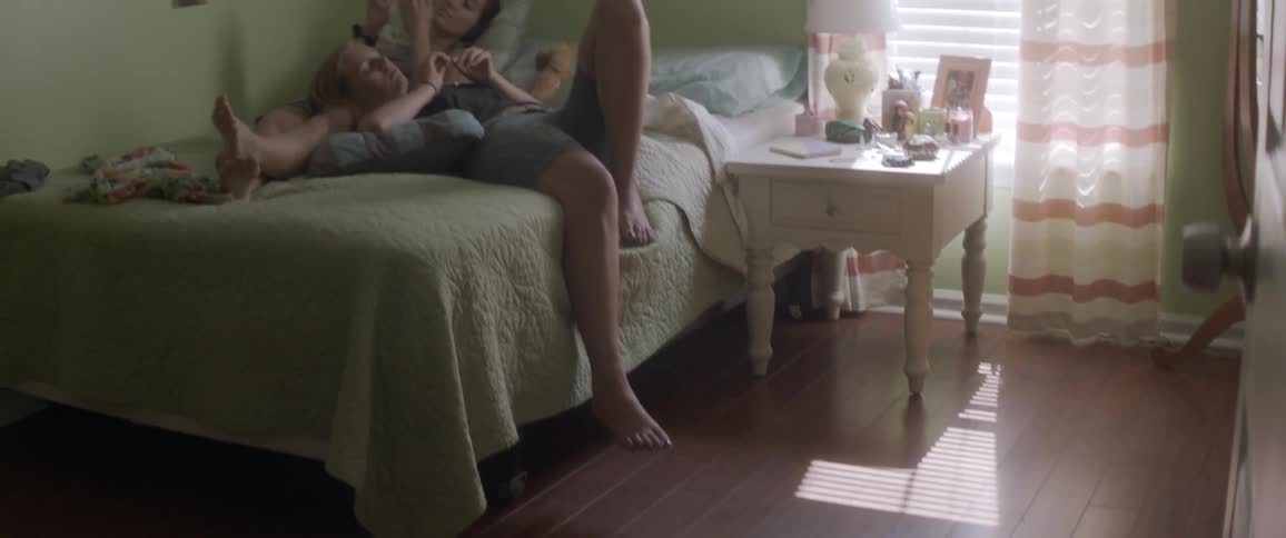 A man and a woman lay on a bed together on a sunny day