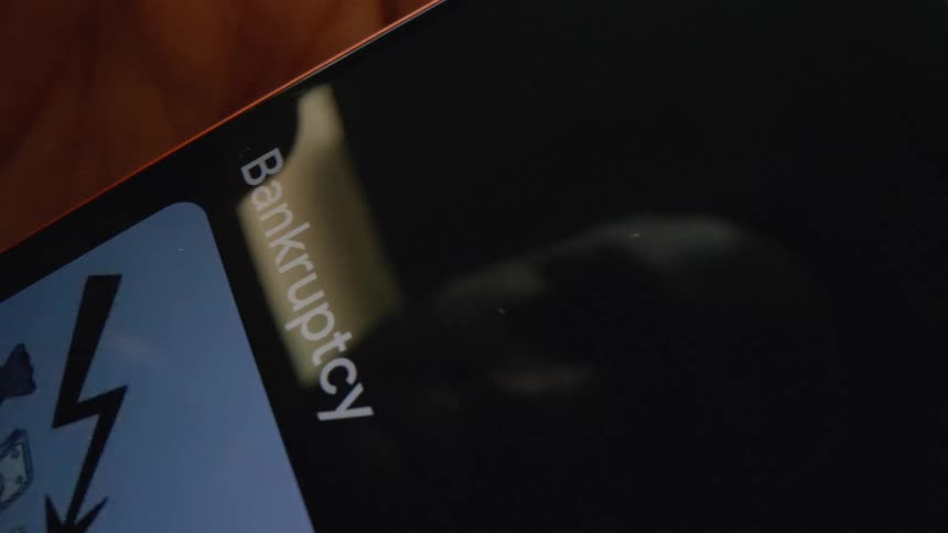 A mans face reflection is seen as he uses his finger to scroll on a close up shot of a smartphone