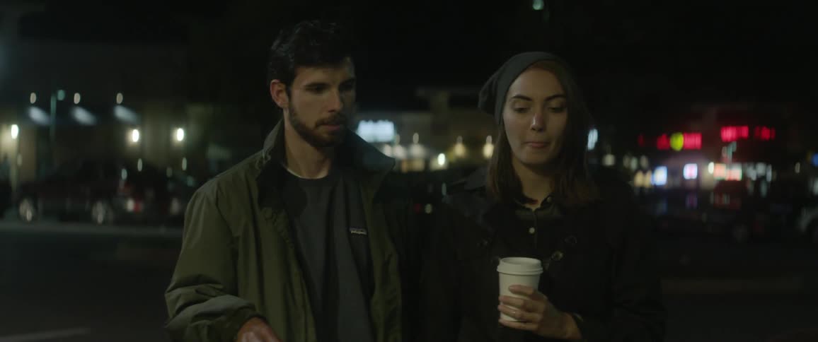 A man and woman talk outside at night