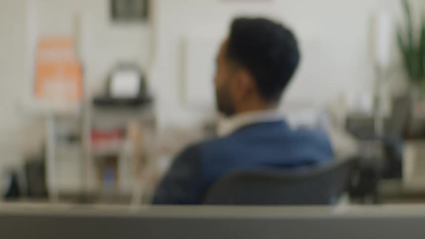 A man sits in an office chair and spins in circles while appearing stressed