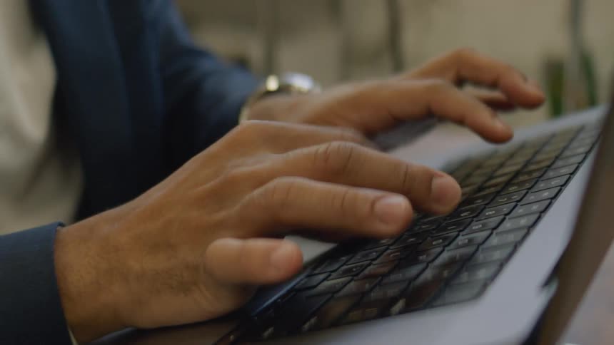 Woman types on a laptop sitting on a laptop stand