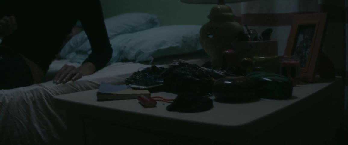 A sleeping woman sits up to put something in a nightstand drawer