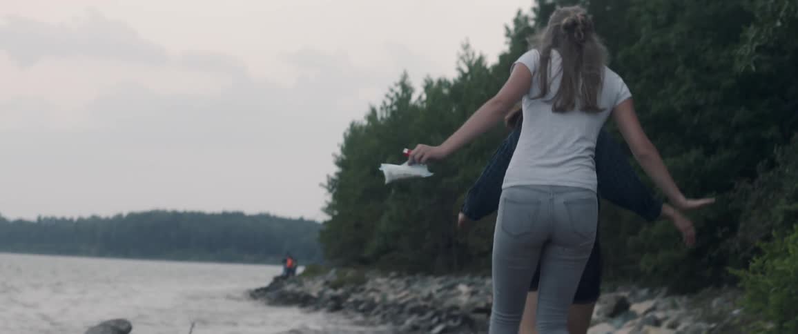 Two women walking on rocks next to lake on windy day