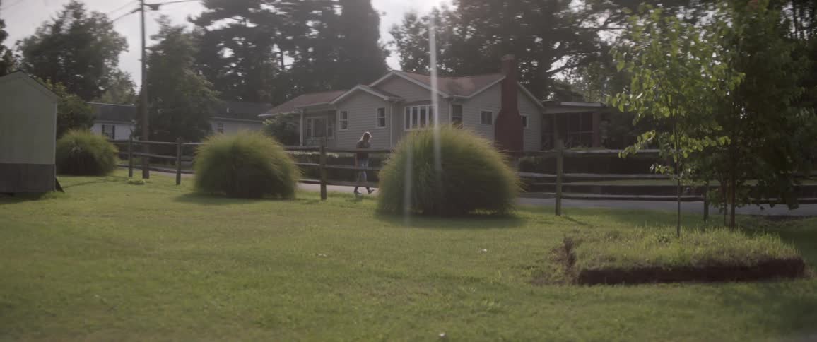 Man walking past a wooden fence in a quiet neighborhood