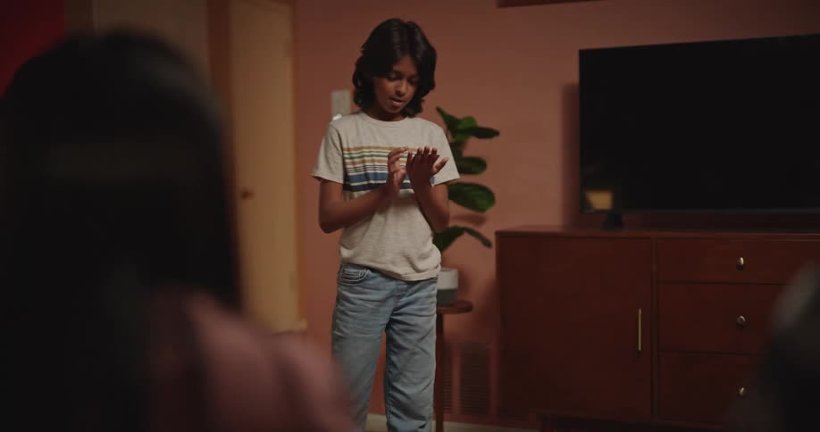 Boy playing charades in the presence of other people in the living room