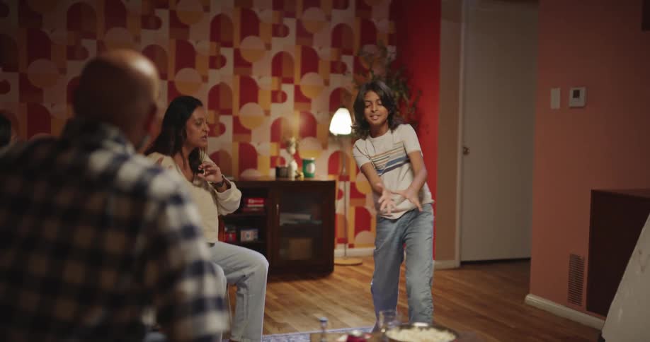 Boy stands in the living room miming while other people try to guess