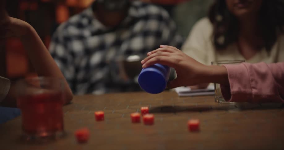 Four people around a small table playing dice in a game of dictatorship