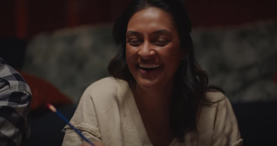 A man and two women laughing while seated indoor at night