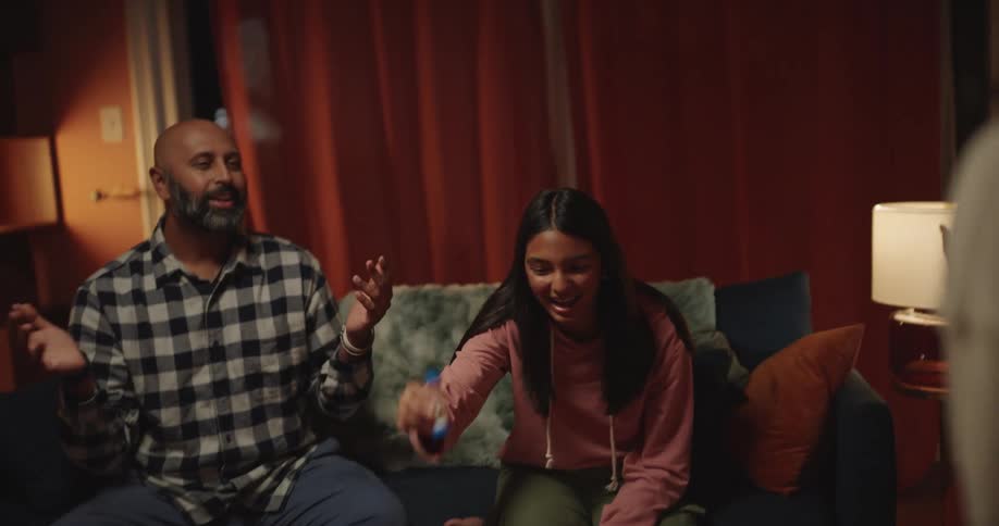 A man and two women play a fun family game as he highfives his smiling teenage daughter