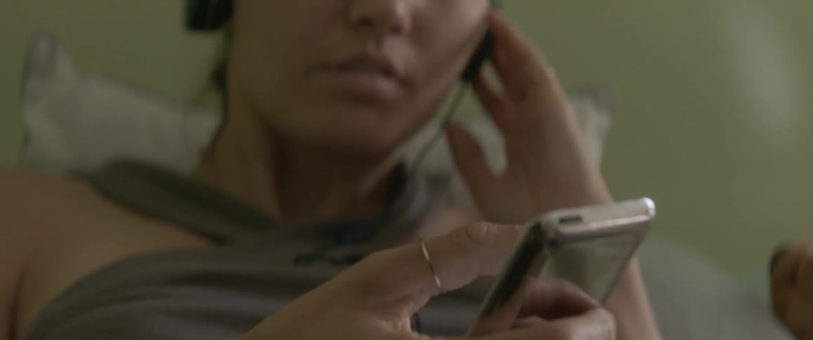 Person taps on a phone while laying in bed