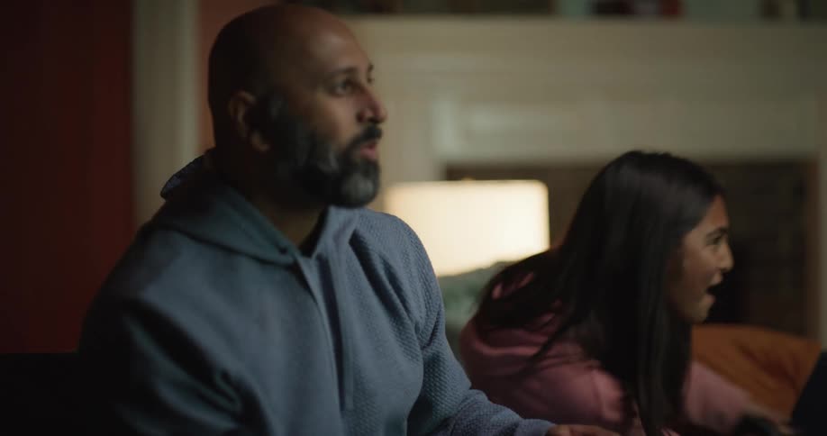 Close up of father and teenage daughter playing video games with controllers while sitting in the living room