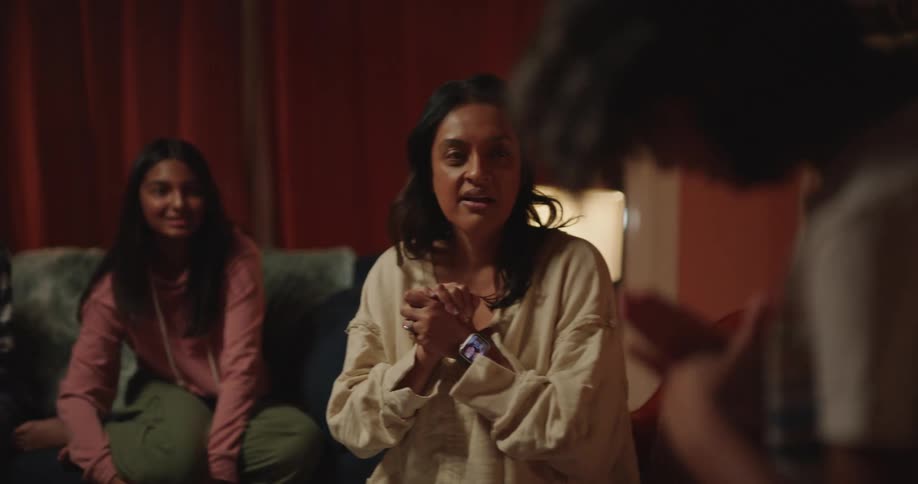 Girl mimes during a family game of charades in their living room at night
