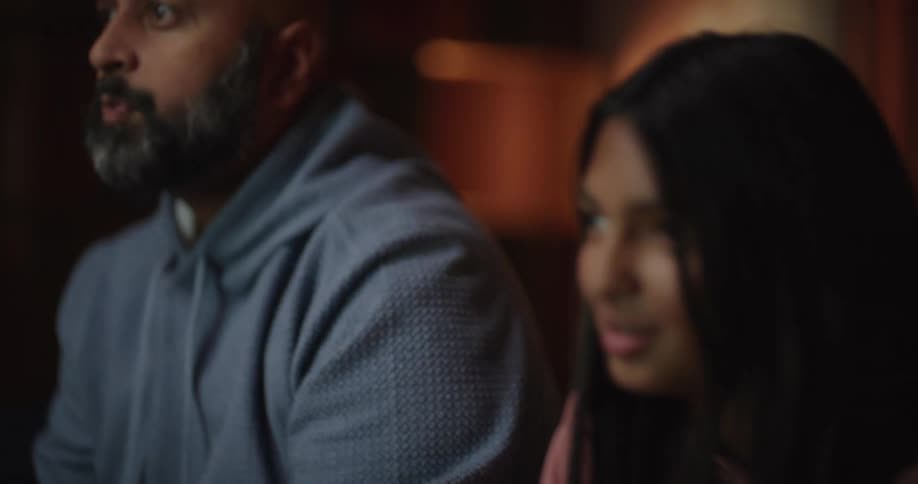Father and daughter play a video game together in their cozy dimly lit living room