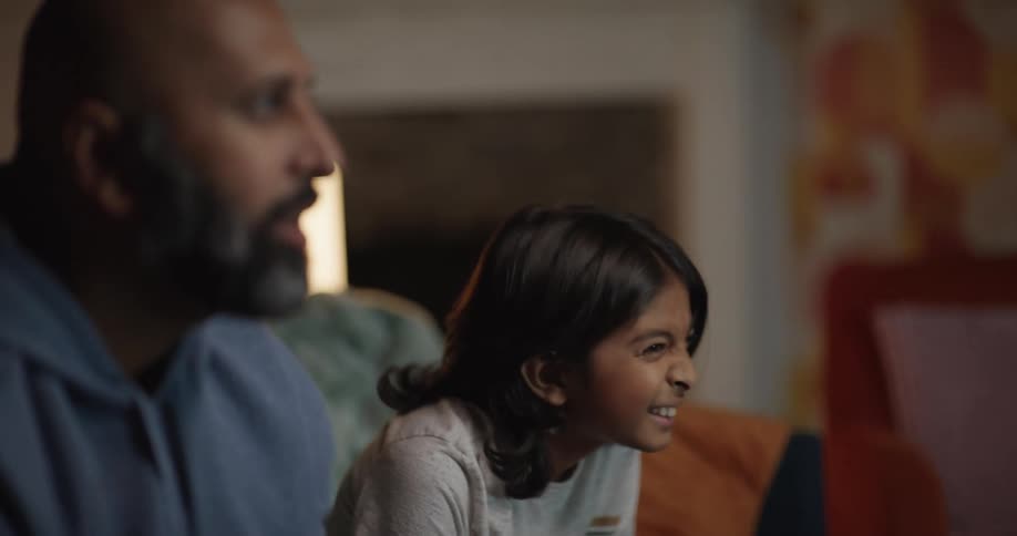 Father and his child play a video game then fist bump while sitting in the living room