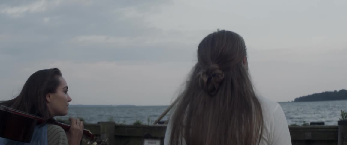 Two women walk outside near water
