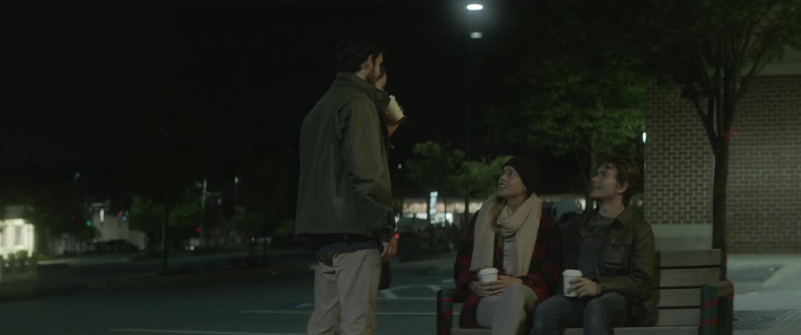 A group of people talk outside at night