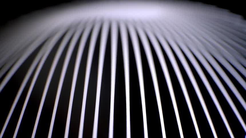 Sharp white lines radiate against a dark background before the focus shifts blurring the geometric pattern into a soft glowing and abstract curved shape