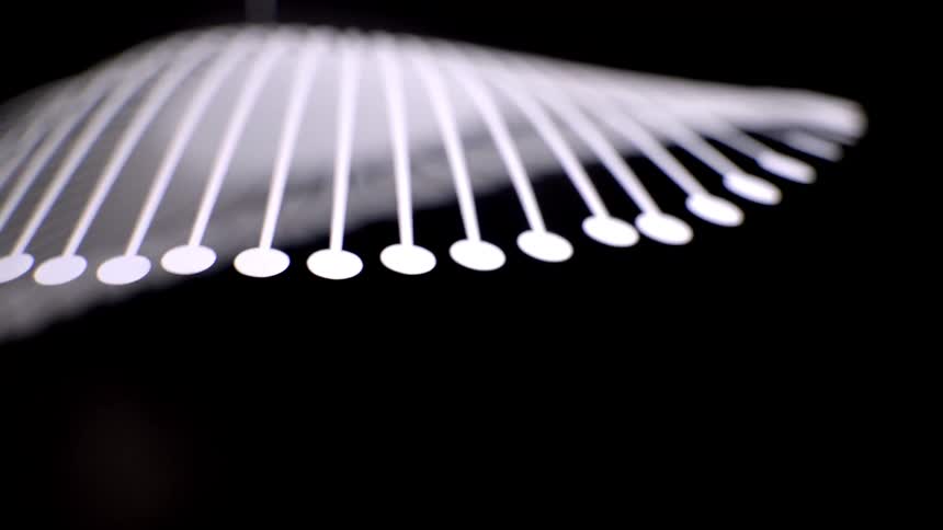 Arched luminous lines with circular points extend into the dark space forming an abstract and fluid pattern
