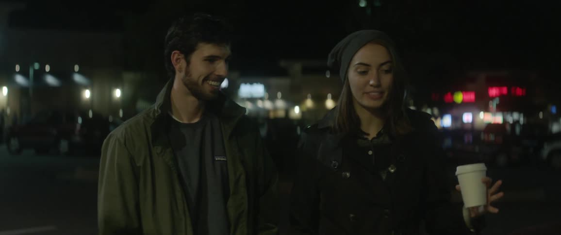 Man and woman stand outside talking at night