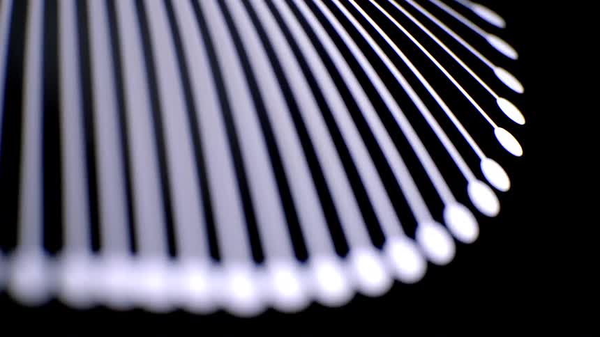 An extremely close view of several white thin rods with circular tips fanned out in a curved pattern that rotate slowly against a solid black background