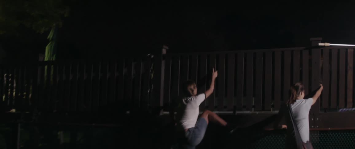 Two women run towards a fence and start to scale it
