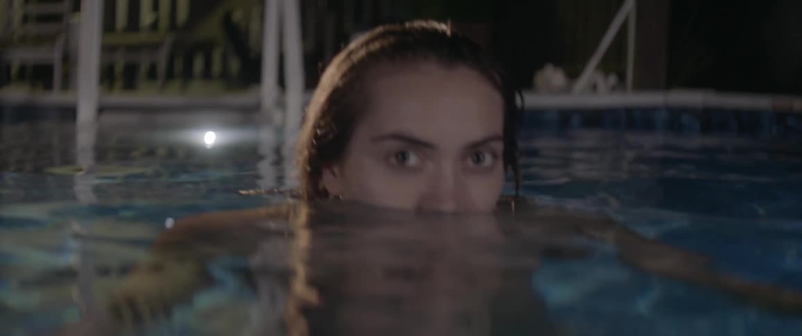 A woman swims in a pool at night