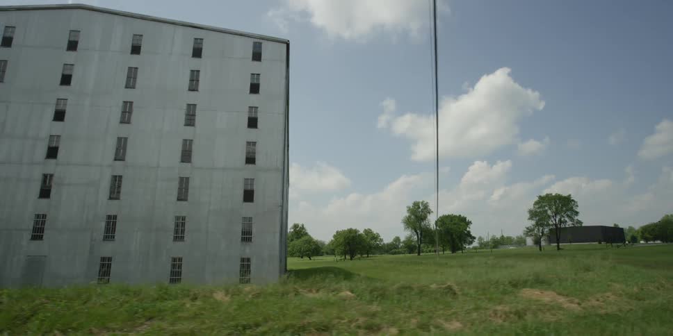 The long green field leads to a building