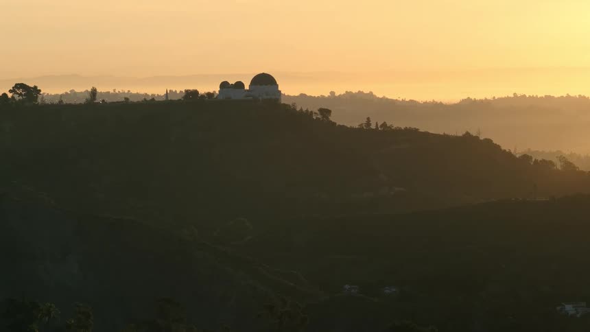 Silhouetted observatory with dome on hilltop at dusk