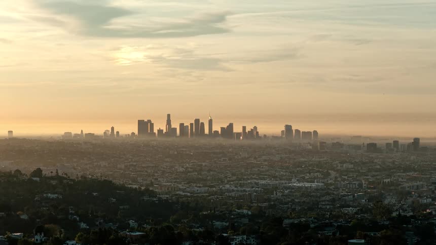 Aerial of a metropolis in the distance at sunset