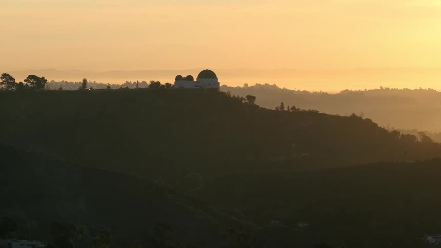 Observatory atop wooded hill at golden sunset