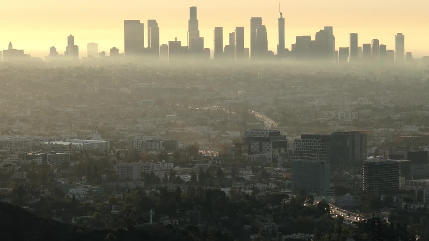Skyscrapers wrapped in golden haze shape the los angeles skyline at dawn