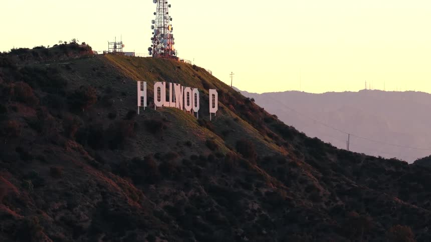 Hollywood sign on a mountainside with a communications tower above