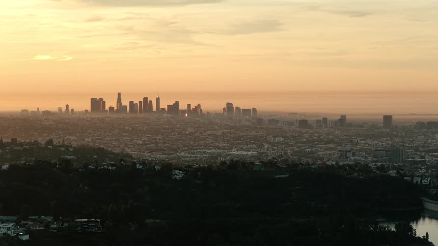 Downtown los angeles glowing at sunset above wooded hills