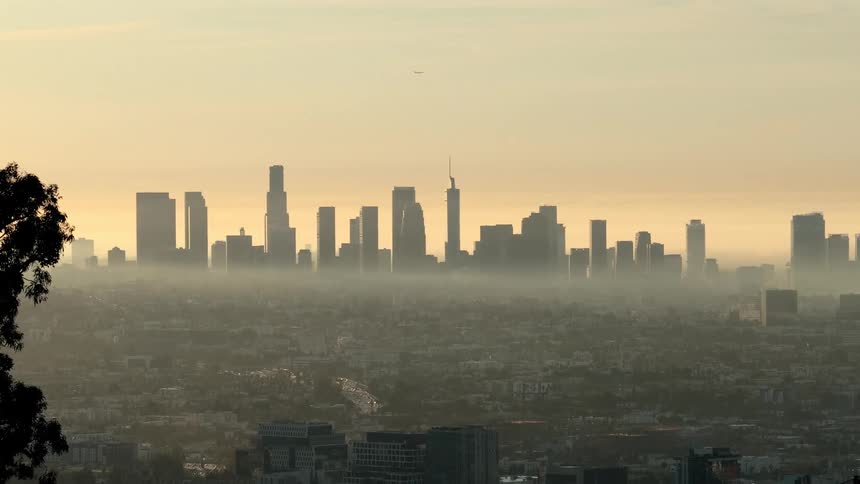 Smog hangs low over a city as the sun rises
