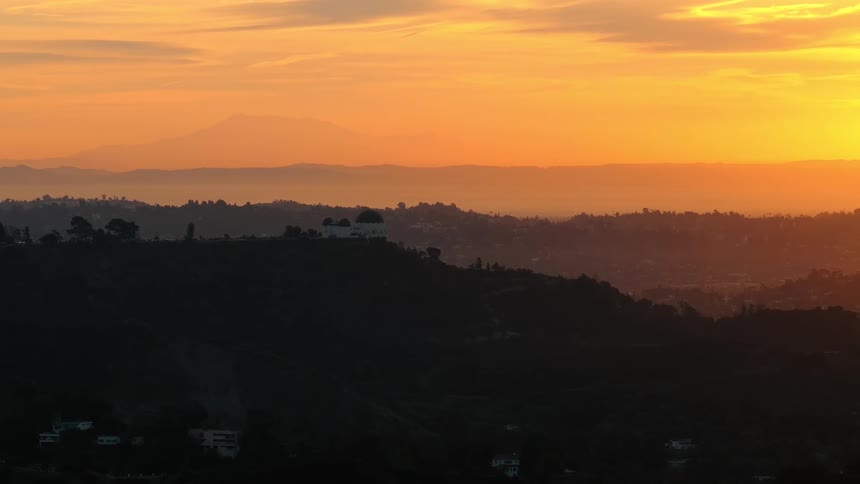 Trees on mountains across the landscape under a colorful cloudy sunset sky