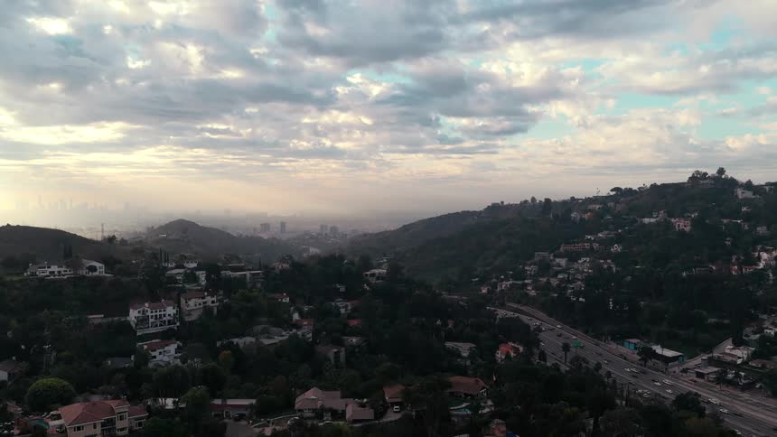 Suburban neighborhood surrounded by hills and divided by a road outdoors during dusk or dawn