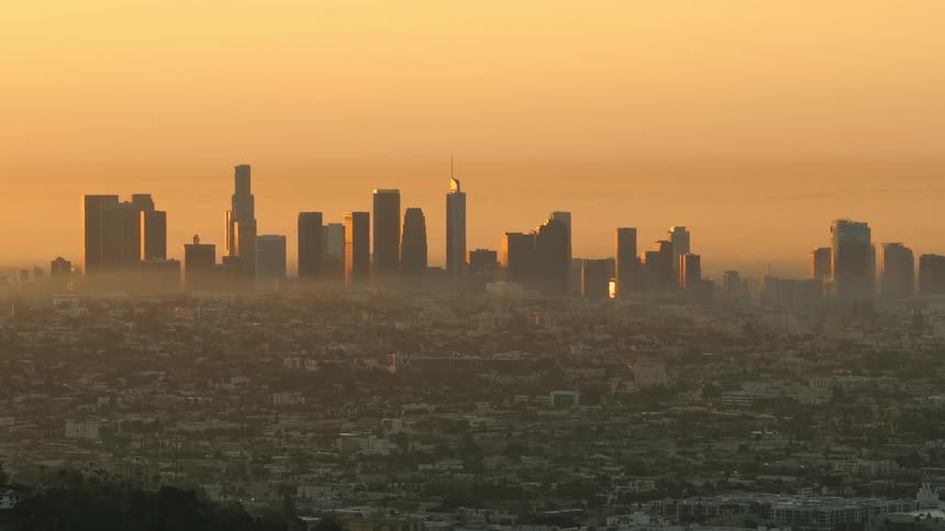 Aerial view of crowded suburbs with towers and skyscrapers on the city skyline in the distance under a hazy sky