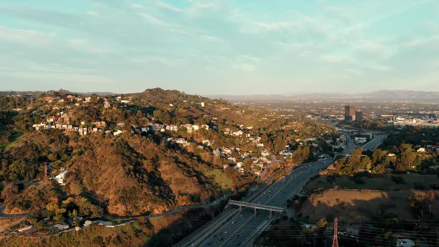Houses and buildings across the mountainside as traffic moves on the highway