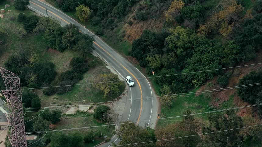 Winding expressway through wooded hills with two moving vehicles