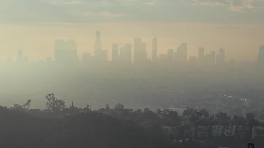 Towers and buildings on the city skyline seen through fog and haze from over a residential area